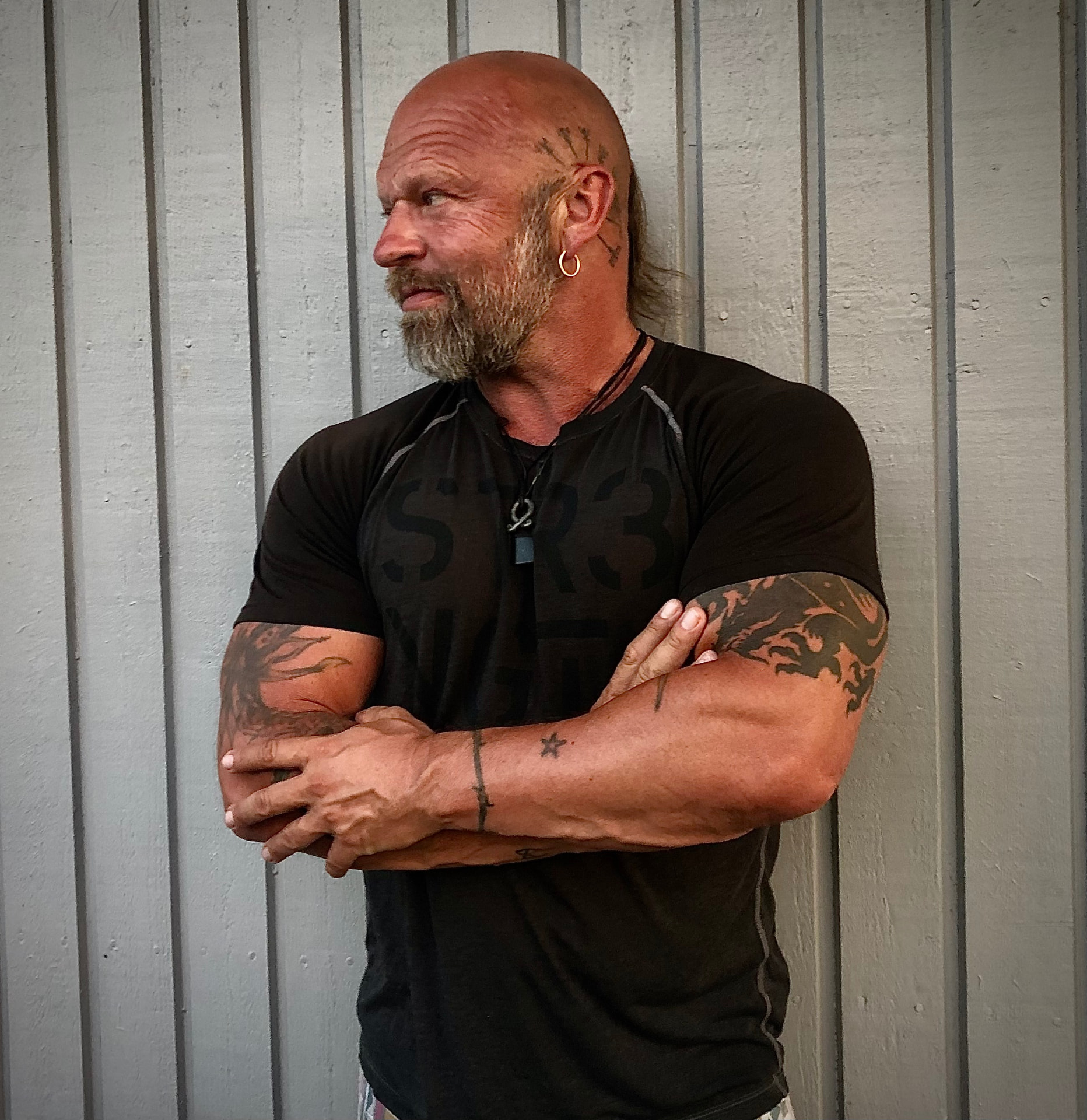 Renzo in a black shirt with crossed arms, looking to his left